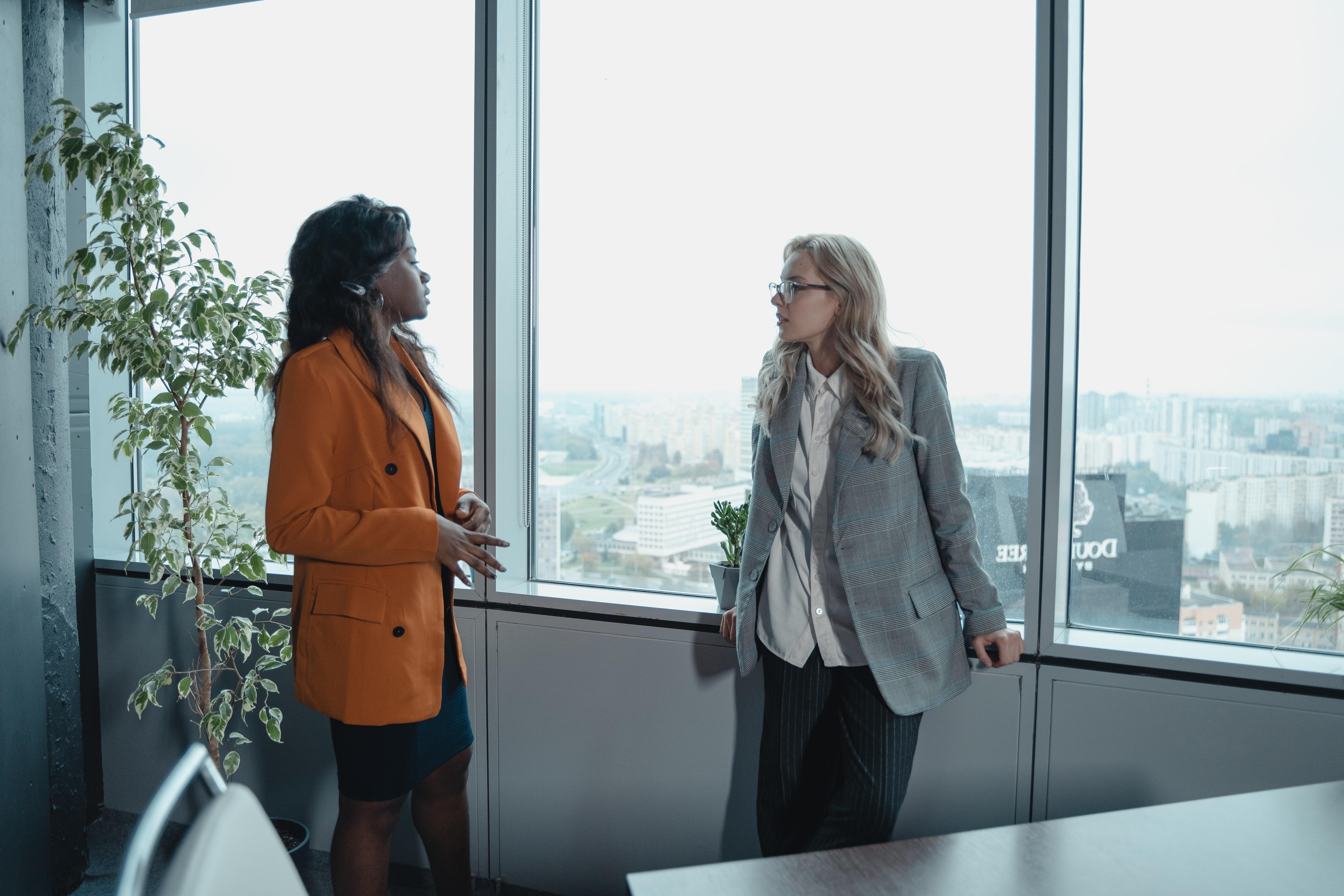 Two business woman talking next to a window